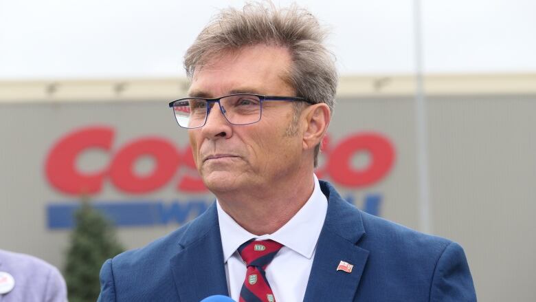 A man's head and shoulders with a Costco logo in soft focus in the distance.