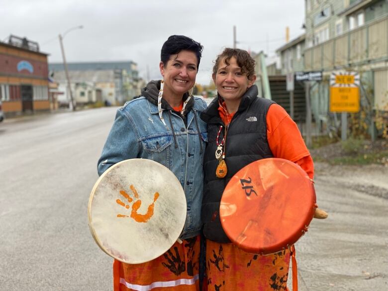 Two women holding drums standing outside