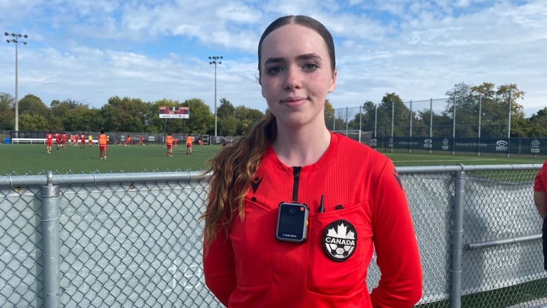 A woman in a refs shirt wearing a body camera.