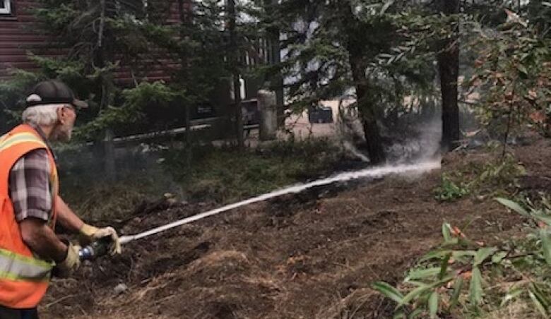 Alan Kimball hoses down the brush beside homes under threat of wildfire in Enterprise, N.W.T.