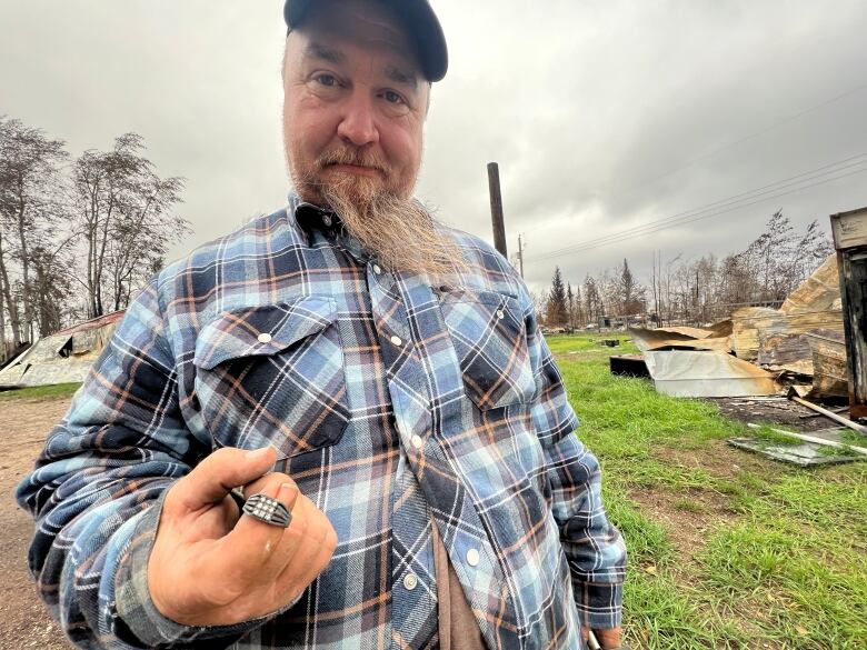 Paul Flamand was able to recover some possessions, such as the ring he is holding in this photo, in the ashes left of his home in Enterprise, N.W.T.