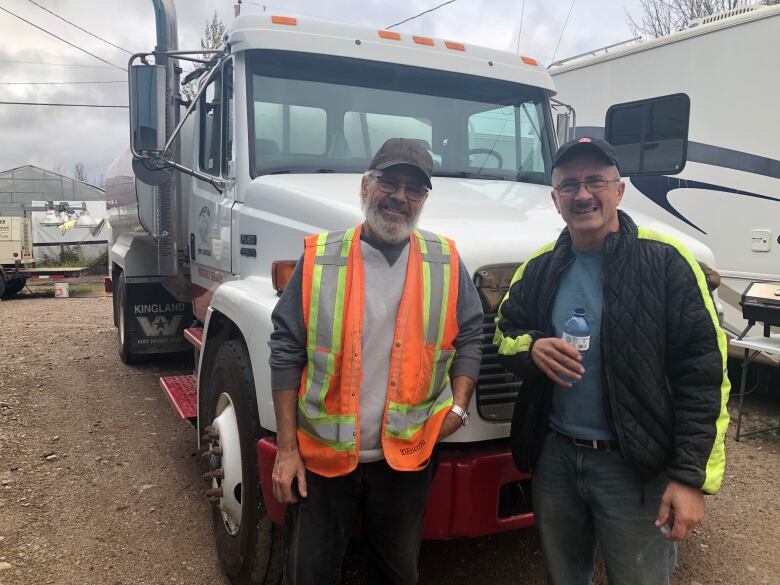 Brothers Alan and Mike Kimball stand in front of the hamlet's water truck they borrowed to fight the wildfire flames that encroached their homes in Enterprise, N.W.T.