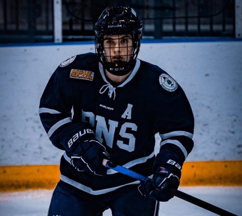 A helmeted hockey player on the ice, holding a stick.