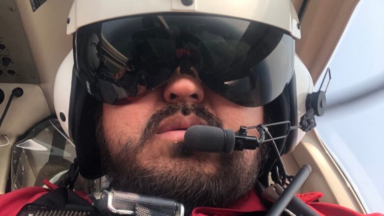 A man wearing a helmet, sunglasses and a headset