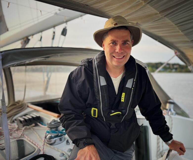 A man in a tilley hat on the deck of a boat. 