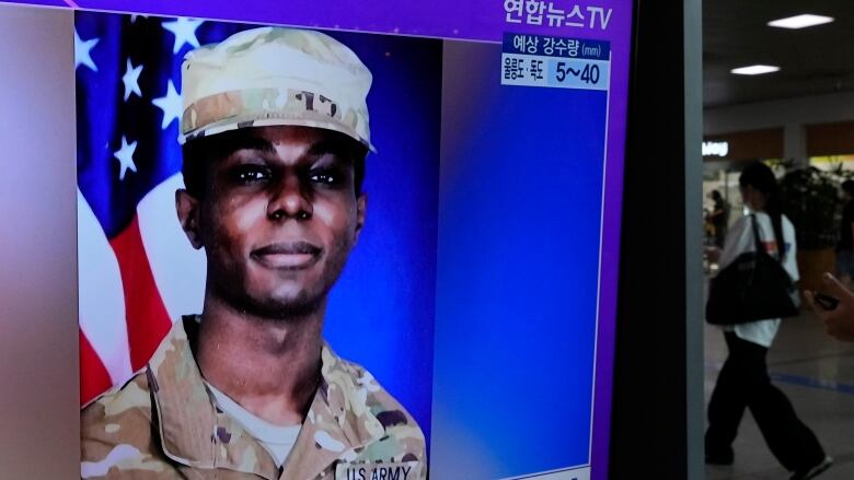 A person in a military uniform is displayed on a public television screen.