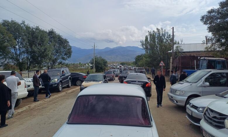 Cars line up on a mountainous road.