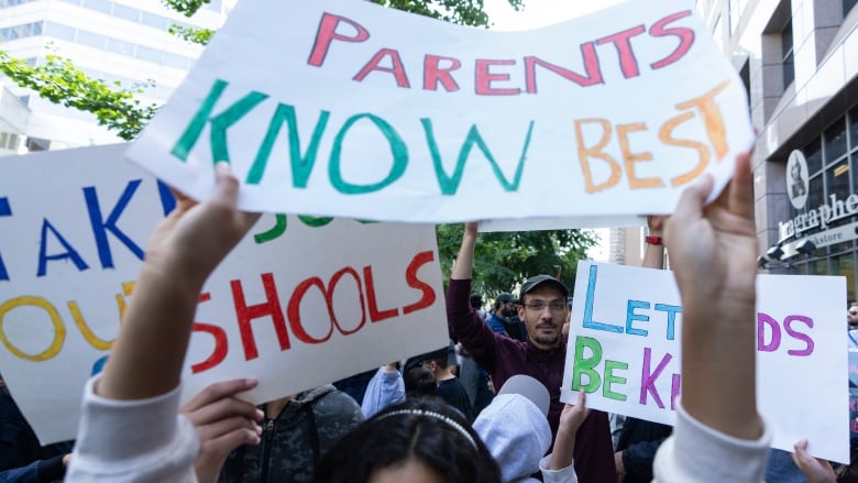 People protesting and holding signs that read 