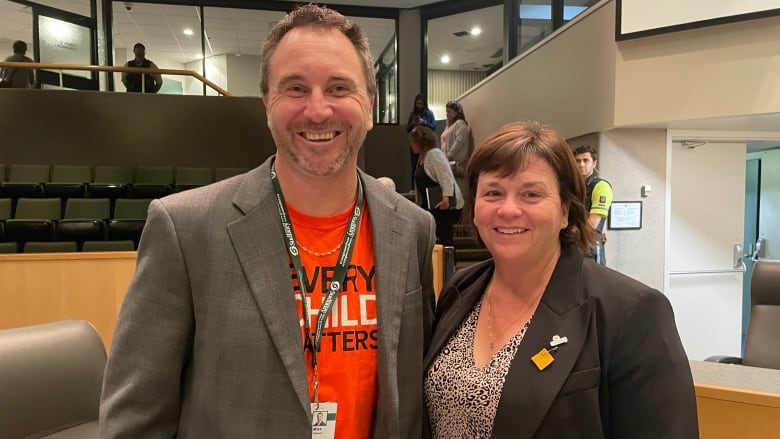 A man wearing an every child matters shirt and a woman in a black blazer.