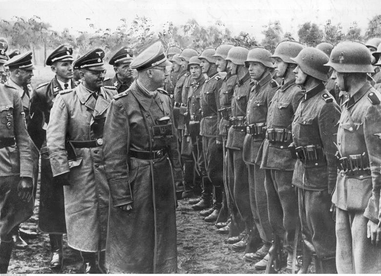 A black and white image of a man in uniform inspecting a line of soldiers.