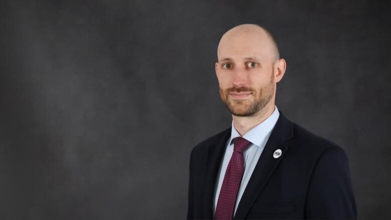 A bald man with a beard wearing a suit.