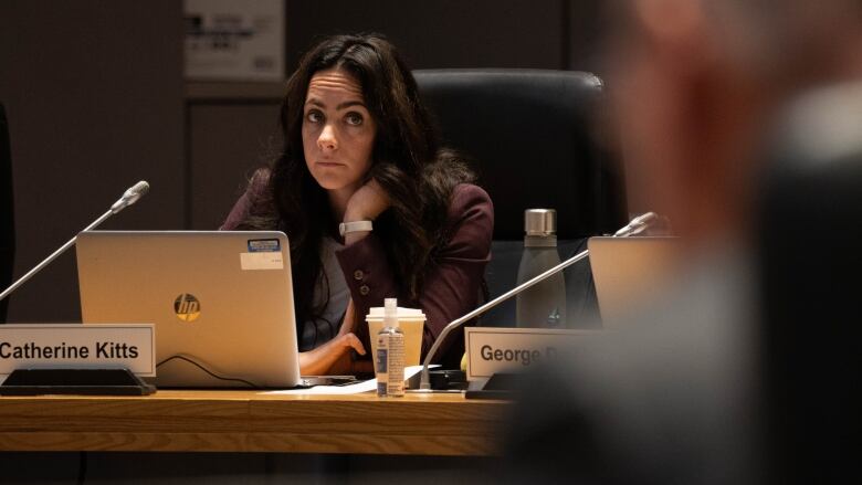 A city councillor listens at a table during a meeting.