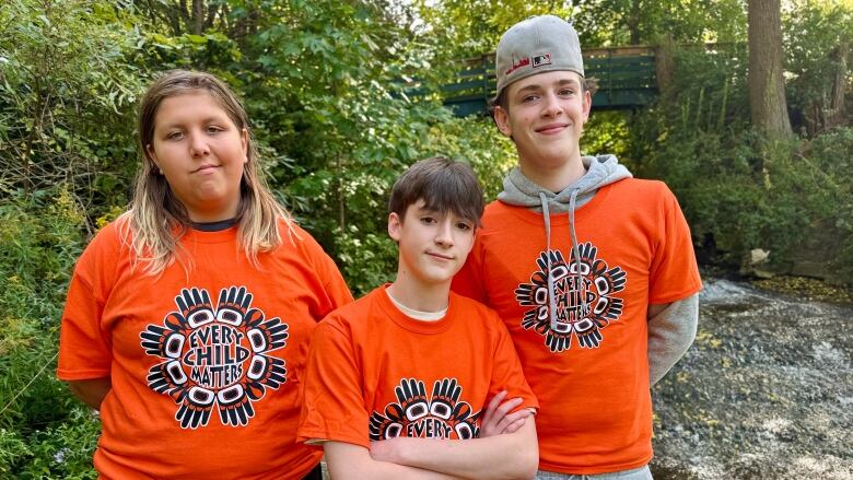 three teenagers stand outside 