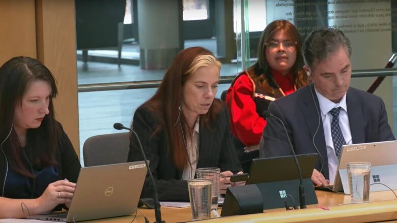 Two women and a man sit at a table. 