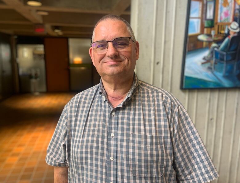 A man wearing glasses smiles at the camera.