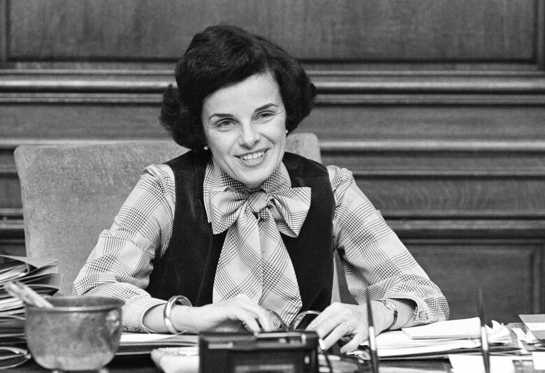 A woman is shown seated in a black and white photograph.