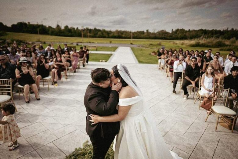 A newly-wed Indigenous queer couple kiss after saying their vows. 