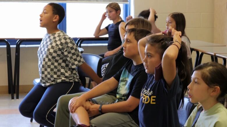 Children sitting in chairs are shown.