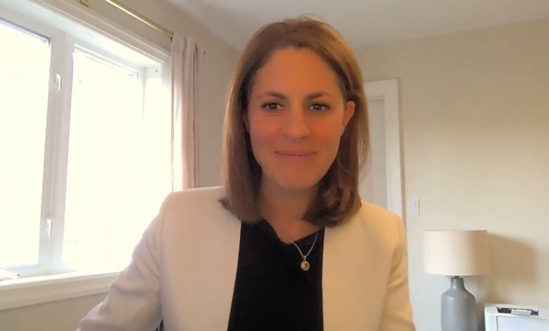 A woman in a white suit is in a home office.