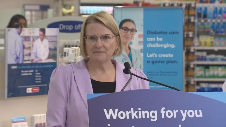 Sylvia Jones stands in front of podium at Shoppers Drug Mart.