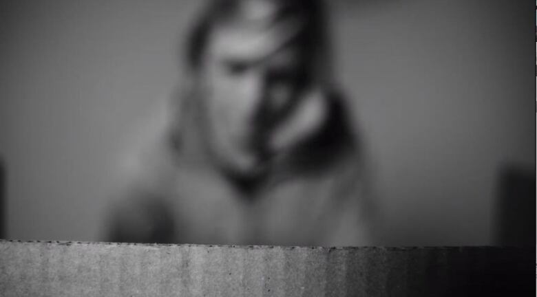 A still of a woman behind a slate of cardboard.