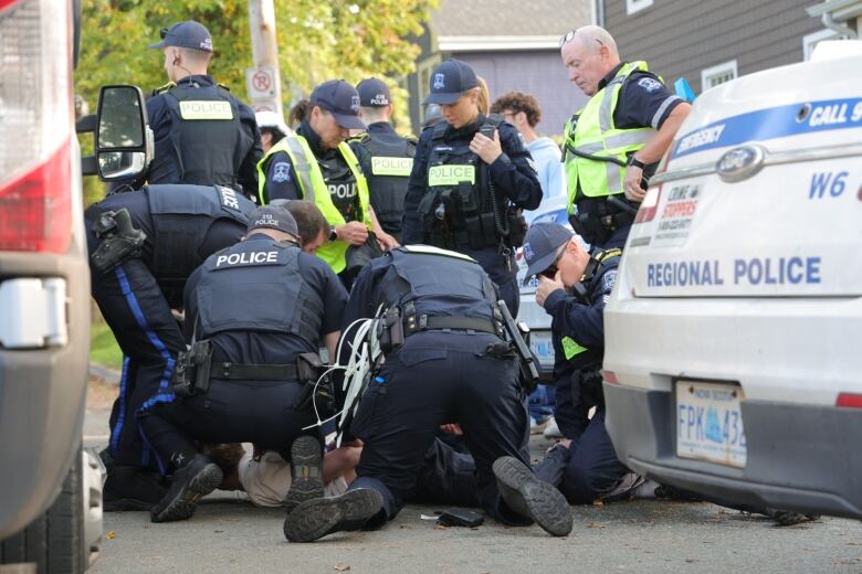 A group of police pin a man on the ground while they attempt to handcuff him.