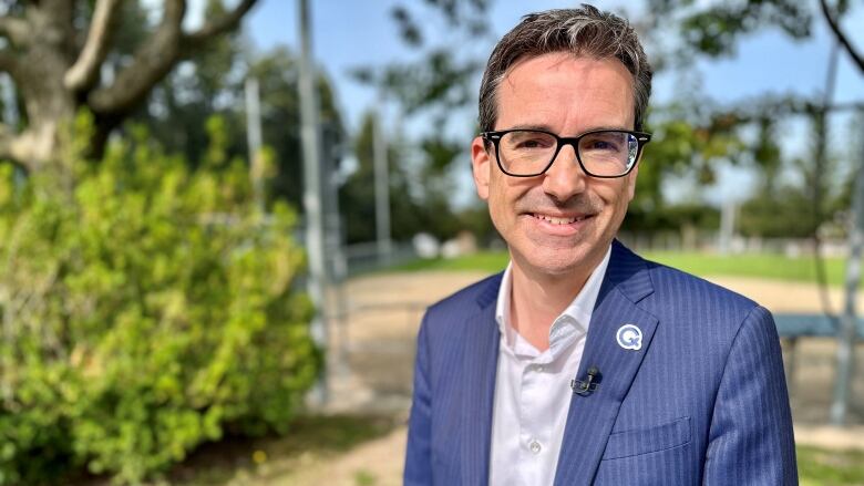 Smiling man in blue suit in a park.