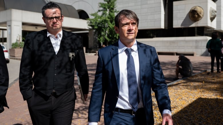 Cameron Jay Ortis, right, a former RCMP intelligence director accused of disclosing classified information, leaves the Ottawa Courthouse following a break in proceedings in Ottawa on Tuesday, Oct. 3, 2023.