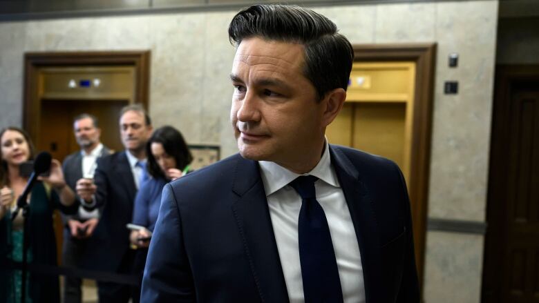 A politician looks to his right as he leaves a news conference in a legislature.