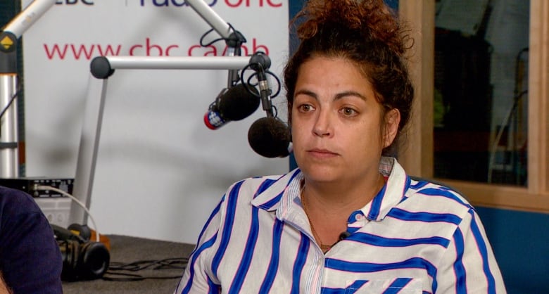 A woman with dark, curly hair pulled back in a ponytail sits in a radio studio.