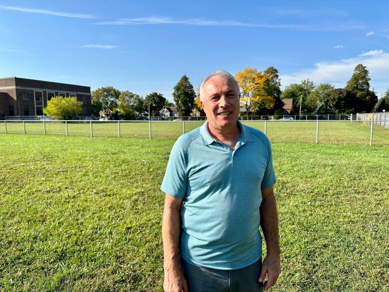 A man stands in front of a vacant school yard.