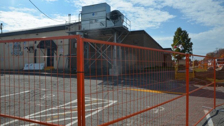 orange construction fencing surrounds a hockey arena 