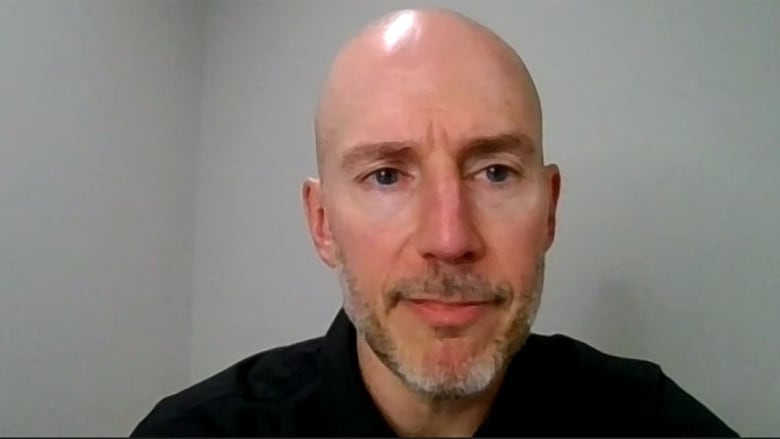 A bald man with a beard, wearing a black shirt.