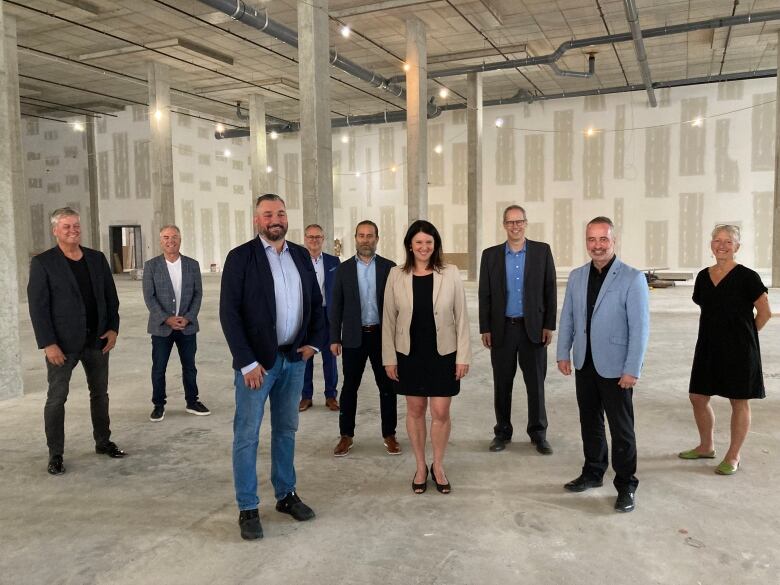 A group of people stands facing the camera at the future site of a grocery store.