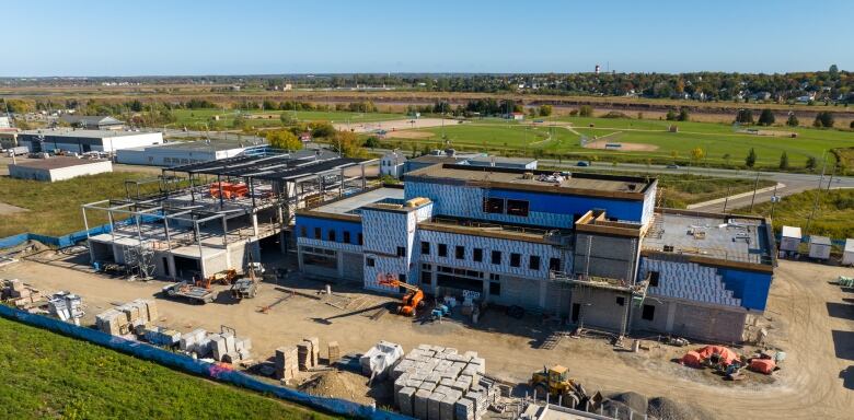 Piles of material and equipment surround a semi-complete two-storey building.