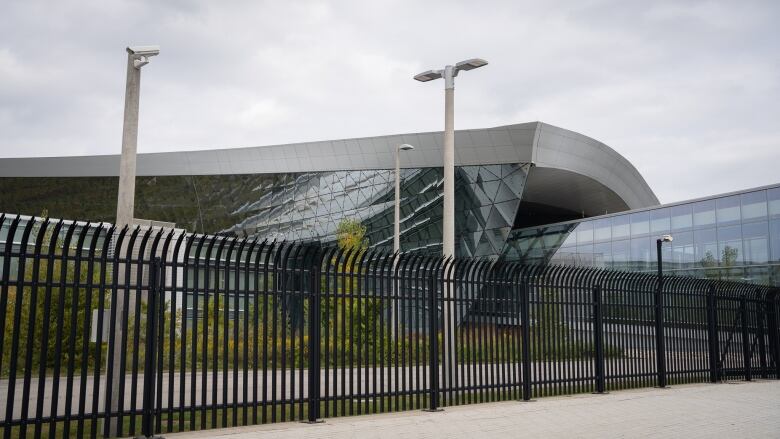 A curvy building behind a fence.