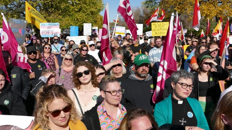 People of all ages rallied at the Saskatchewan Legislature. Some hold handmade signs or flags.