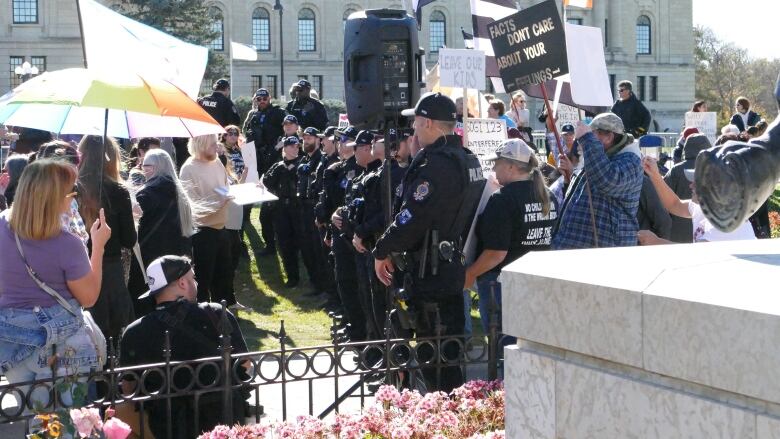 Police form a line between two groups at the Saskatchewan legislature Tuesday. On the left are protestors against the policy while the protestors on the right are groups in favour of the pronoun policy. 