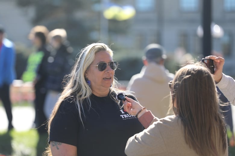 A woman with blonde and brown hair, wearing a black shirt with 