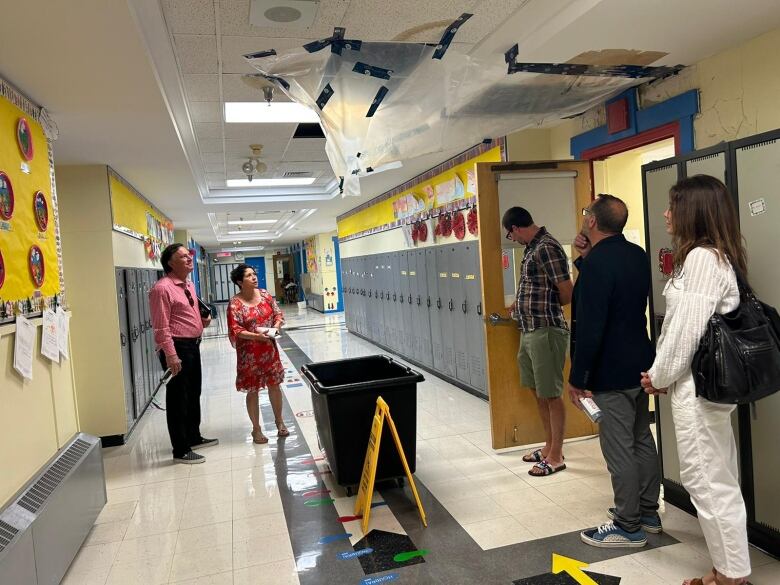 Saskatchewan Party MLA, Gordon Wyant is pictured standing below a hole in the ceiling of Monique-Rousseau elementary school.