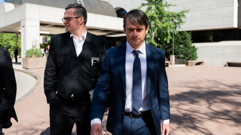 Cameron Jay Ortis, right, a former RCMP intelligence director accused of disclosing classified information, leaves the Ottawa Courthouse following a break in proceedings in Ottawa on Tuesday, Oct. 3, 2023.