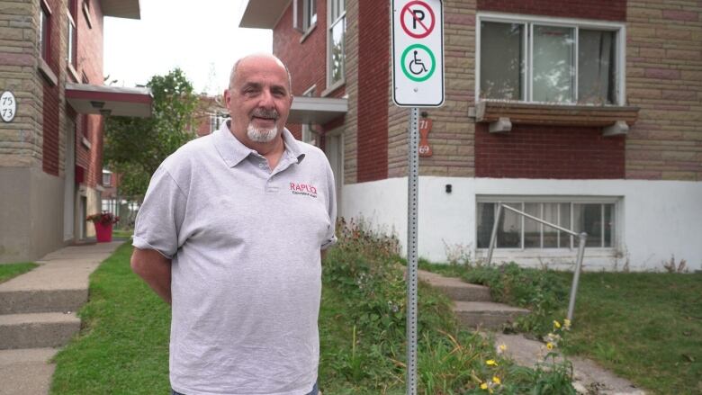 A man stands near a handicapped parking sign.