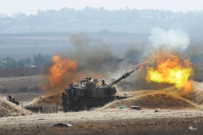 An Israeli tank fires a shell from Israel toward the Gaza Strip