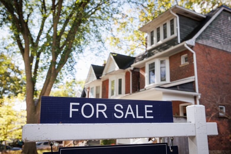 A for sale sign outside a house for sale in Toronto.