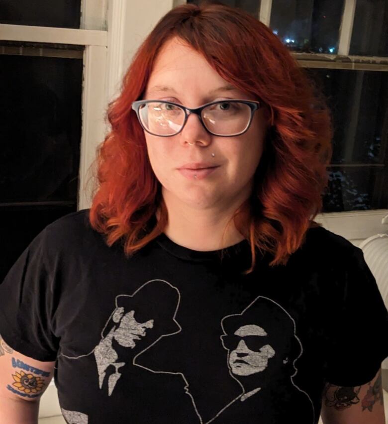 A woman with red hair who is wearing glasses.