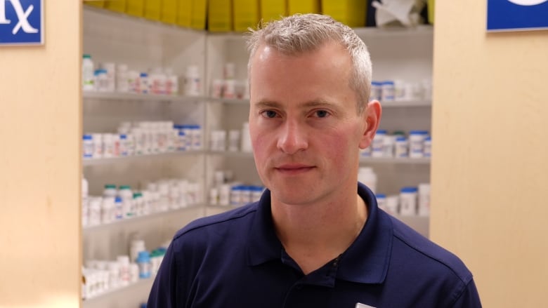 A man with short grey hair in a blue polo shirt that says 