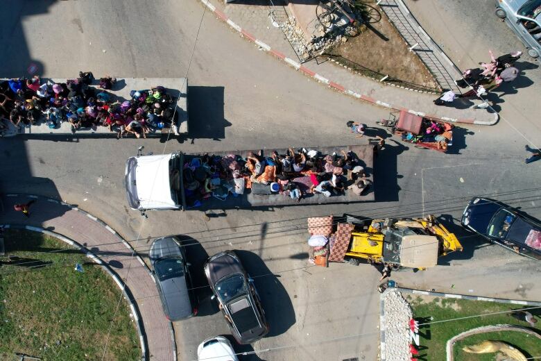 An aerial view of refugees on flatbed trucks.