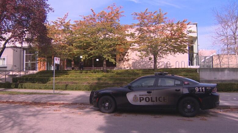 A police car parks in front of a synagogue.