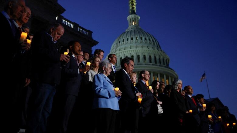 People standing at dusk outside the Capitol dome