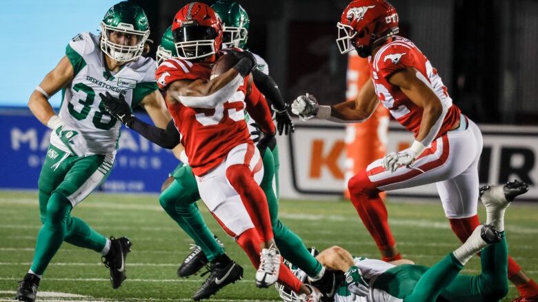 Saskatchewan Roughriders defensive back Jayden Dalke looks on as Calgary Stampeders running back Ka'Deem Carey runs away with the ball in hand